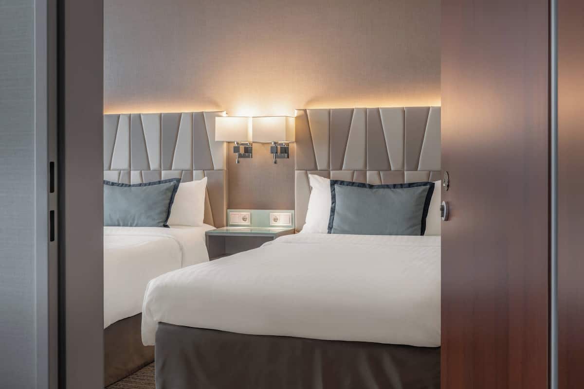 Une chambre d’hôtel avec deux lits, chacun doté d’une tête de lit et de tables de chevet.