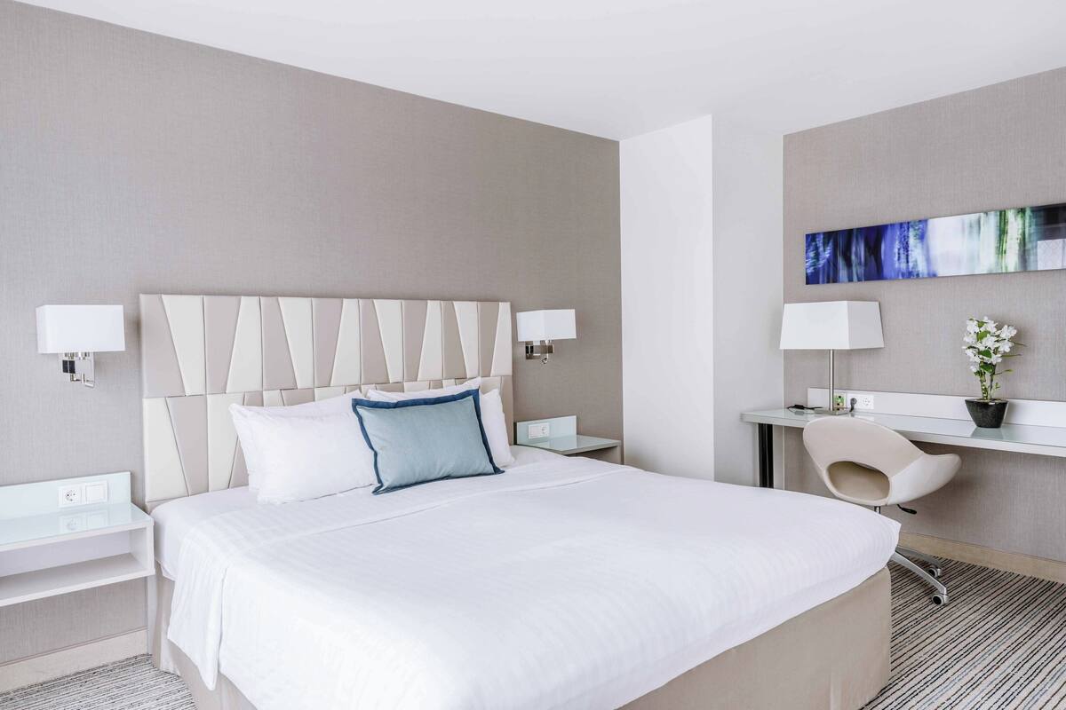Une chambre d’hôtel moderne avec un grand lit, des tables de chevet, un bureau et une chaise.