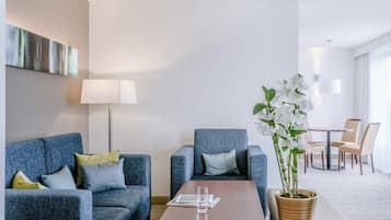 Una habitación de hotel moderna con un conjunto de sofá azul, una mesa de centro de madera y una orquídea en maceta.