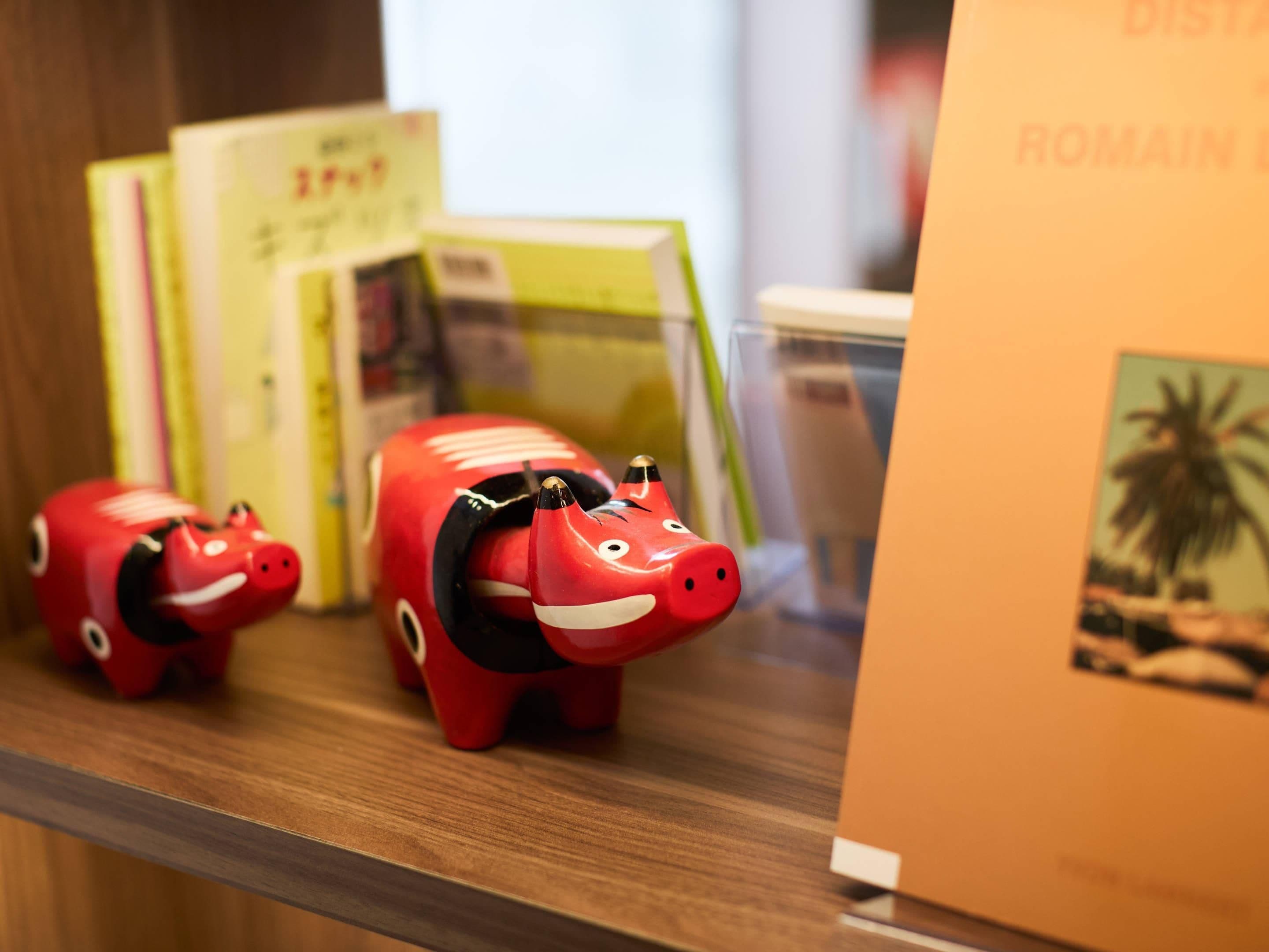 A shelf with books and a piggy bank.