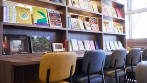 Una biblioteca con estanterías, sillas y una ventana.
