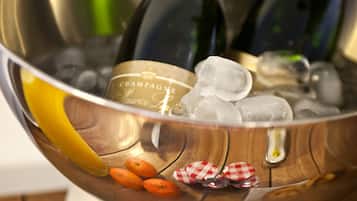 A metallic bowl containing ice cubes, a bottle of champagne, and some orange slices.