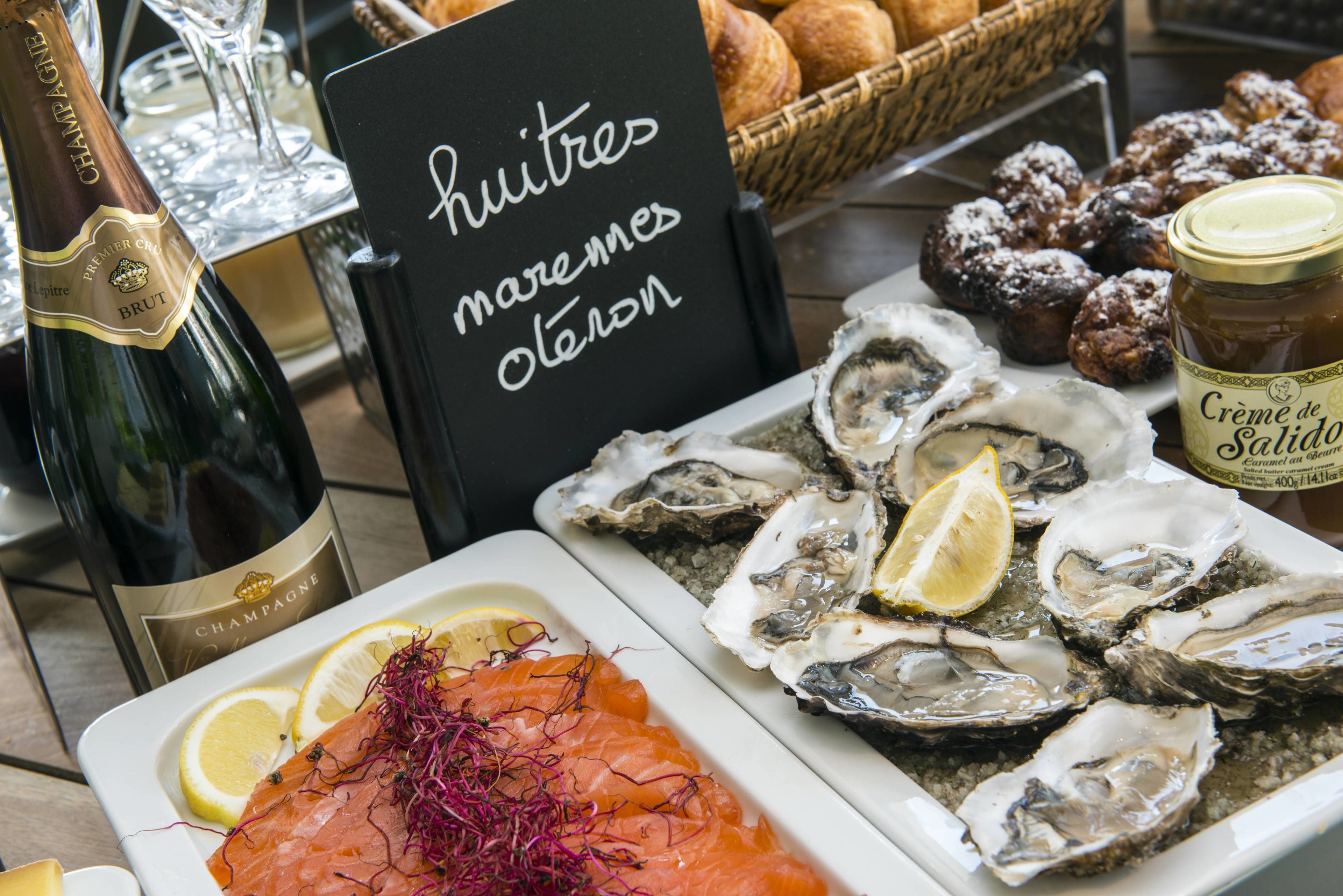 Una mesa con mariscos, incluyendo ostras y salmón, y una botella de champán.