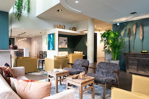 A modern hotel lobby with a seating area, a dining space, and a reception desk. - Best Western Premier Le Masq Hotel (La Rochelle)
