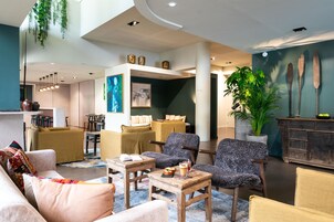 Un moderno vestíbulo de hotel con una zona de estar, un comedor y una recepción.
