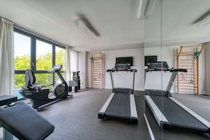 Une salle de sport à domicile équipée de tapis de course, d’un vélo d’appartement et d’un banc de musculation.