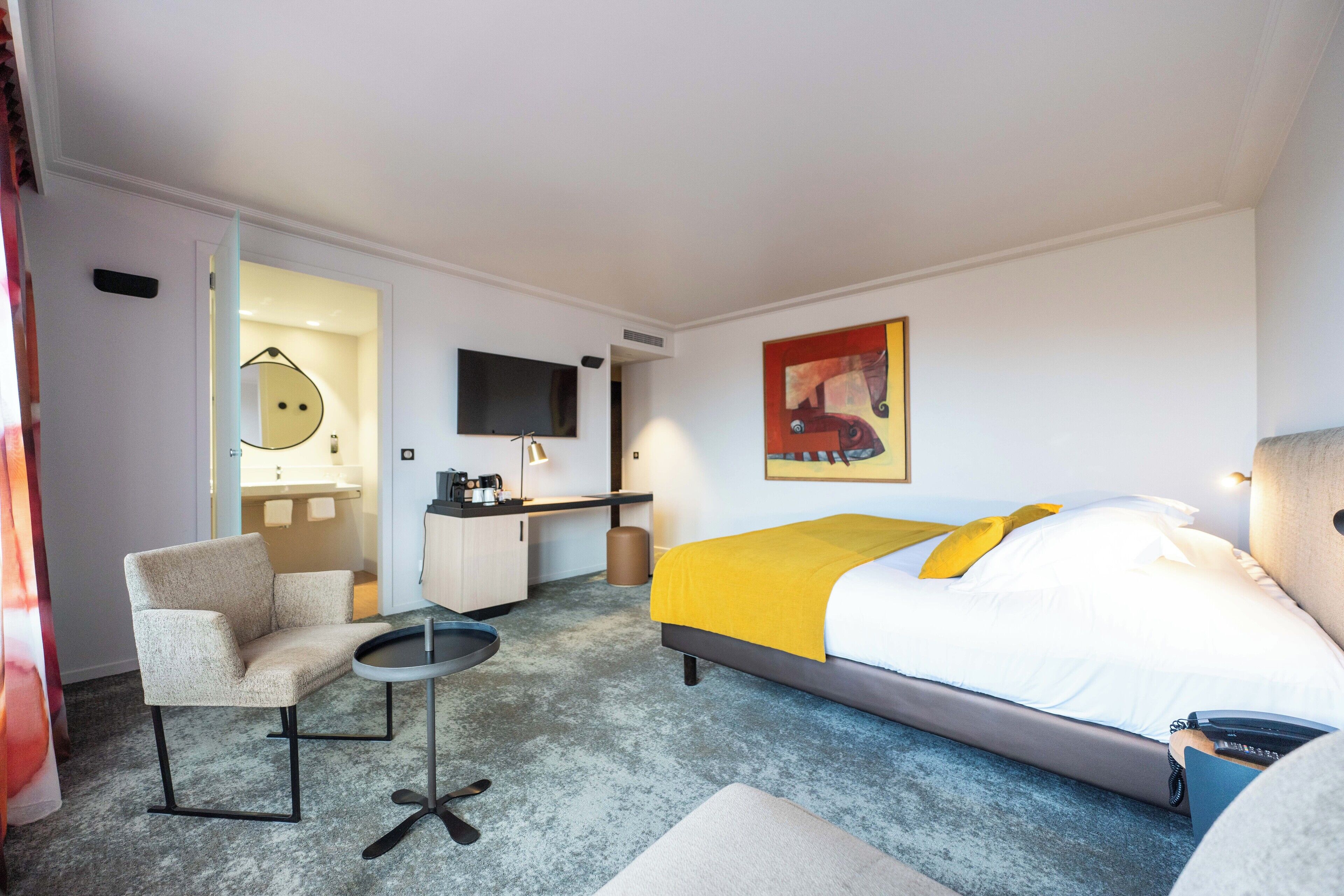 Une chambre d’hôtel comprenant un lit, un bureau, une chaise, une petite table et un téléviseur.