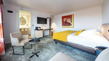 Une chambre d’hôtel comprenant un lit, un bureau, une chaise, une petite table et un téléviseur.