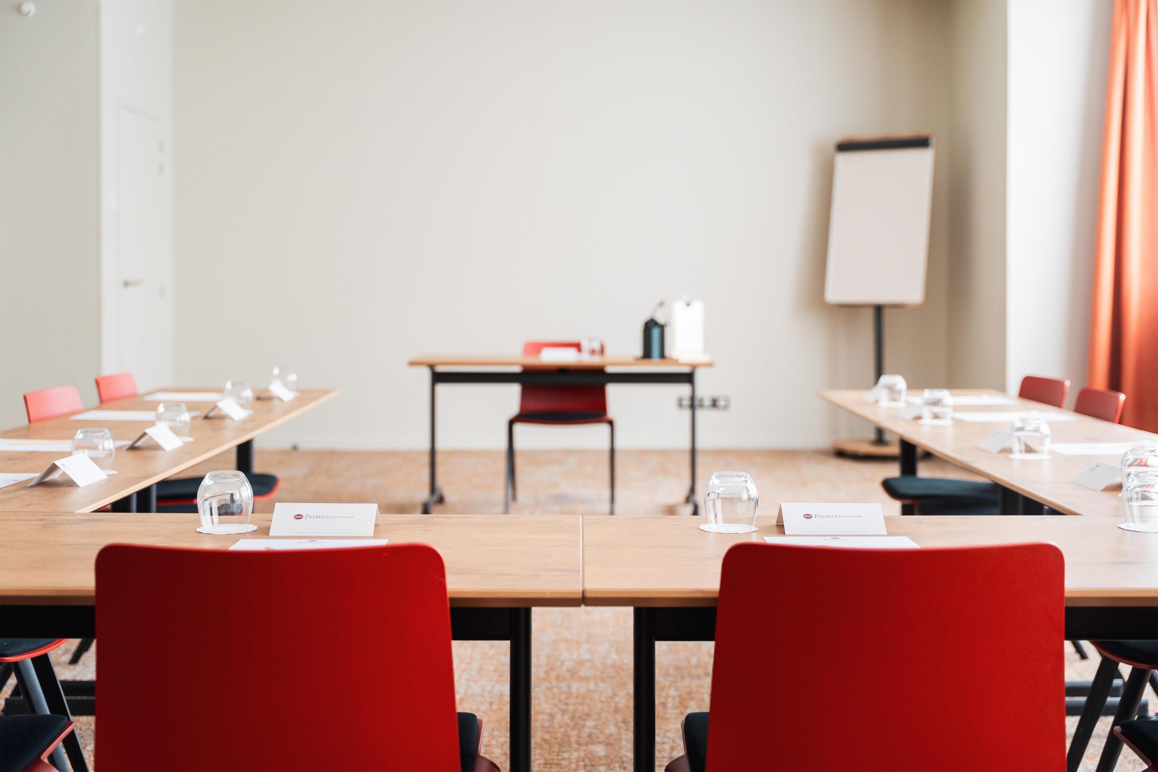 A conference room with a long table, red chairs, nameplates, and a whiteboard.