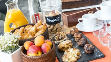 A breakfast buffet with pastries, fruits, and a bottle of juice.