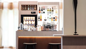 Un espace bar avec un comptoir en bois, des étagères remplies de bouteilles et deux tabourets de bar.