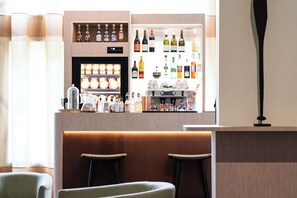 Un espace bar avec un comptoir en bois, des étagères remplies de bouteilles et deux tabourets de bar.