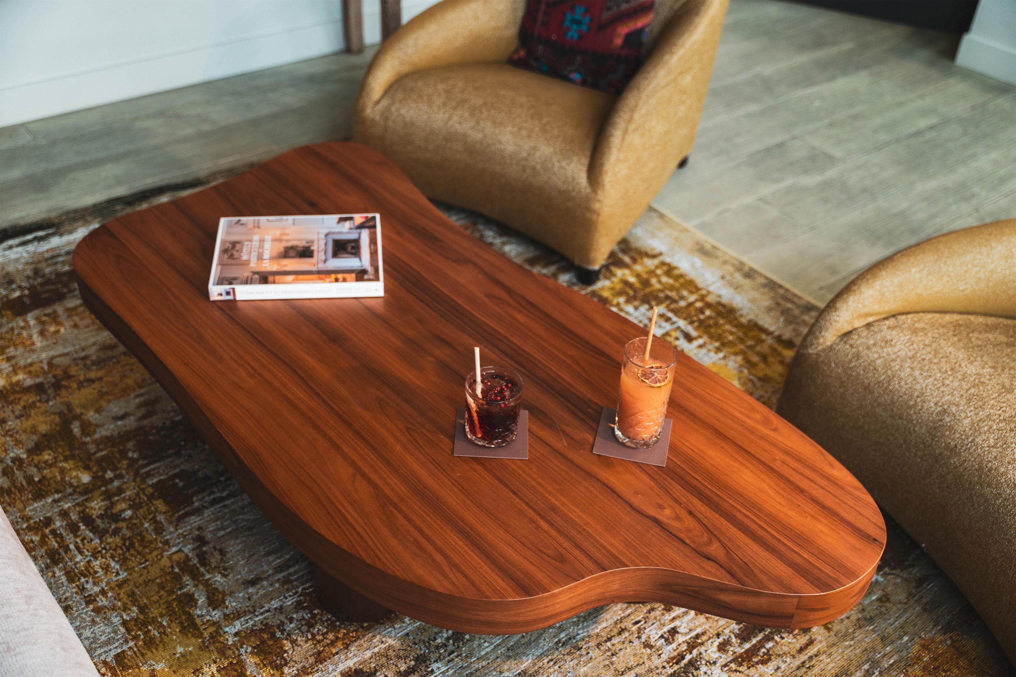 A wooden coffee table with two drinks and a magazine.