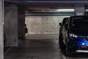Un parking avec des piliers en béton et une voiture bleue garée dans un espace réservé à cet effet.