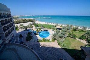 Een resort met een zwembad, strand en palmbomen.
