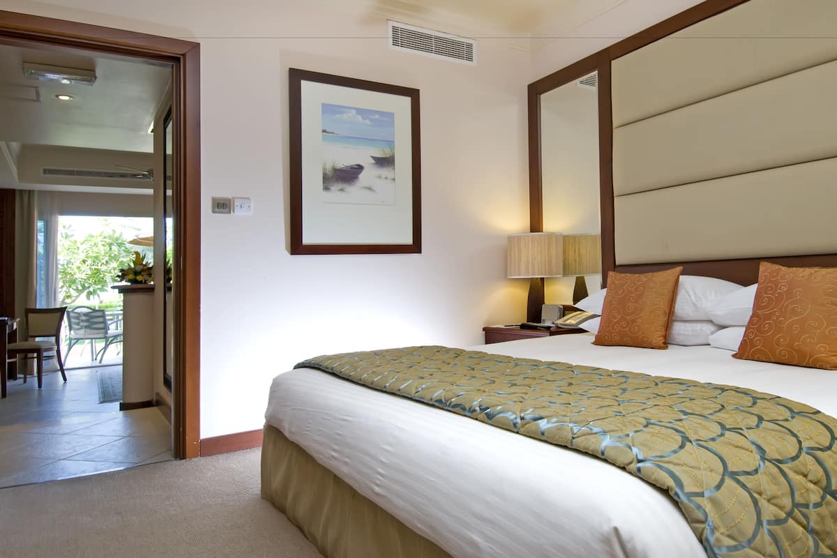 A hotel room with a bed, a nightstand, a lamp, and a framed picture on the wall.