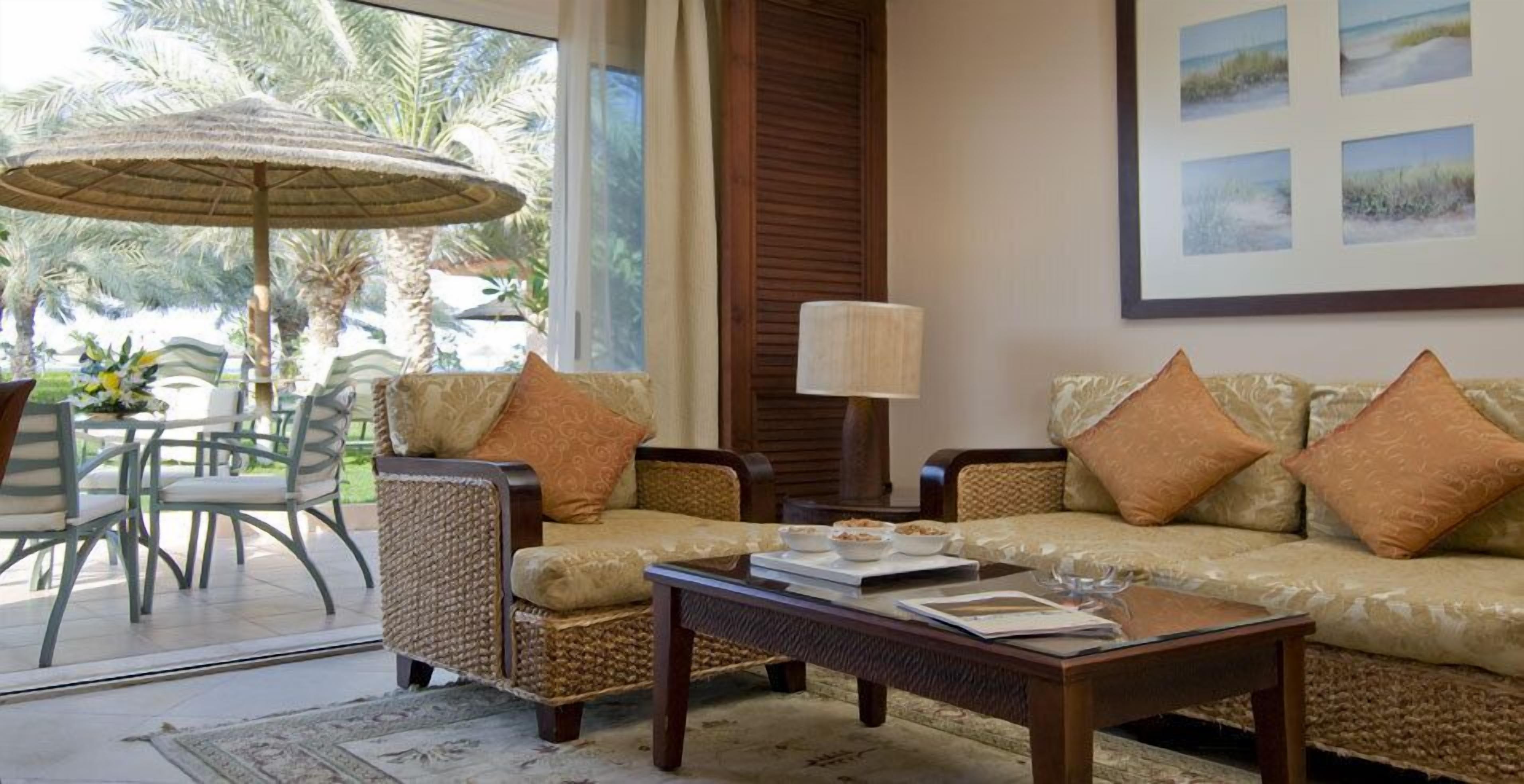 A cozy living area with wicker furniture, a coffee table, and a large umbrella.