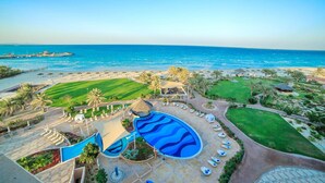 Un complexe hôtelier doté d’une grande piscine, d’une plage et de palmiers.