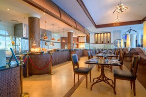 Een ruim restaurant met hoge plafonds, moderne verlichting en diverse zitmogelijkheden.