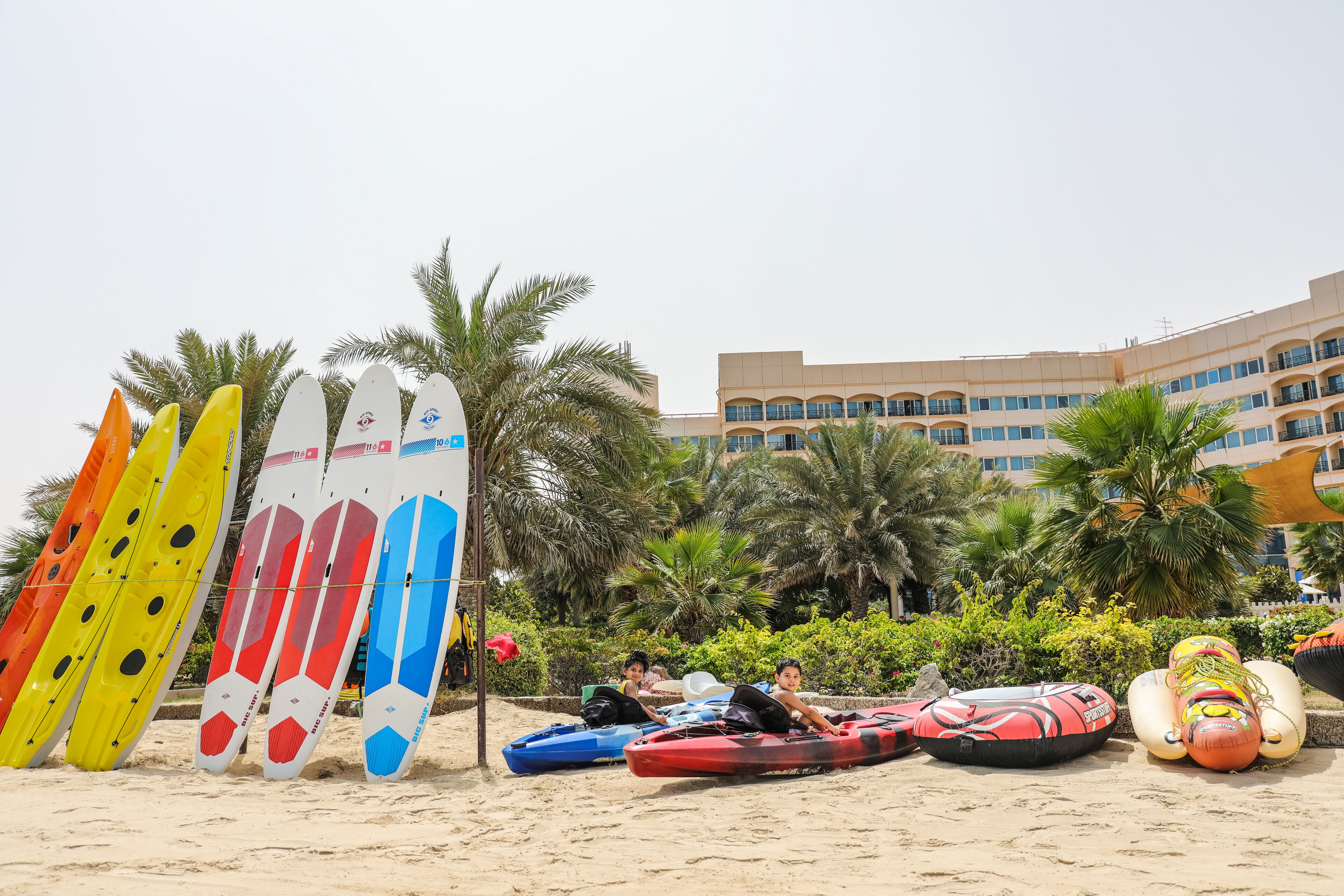 A beach with kayaks and a building in the background.