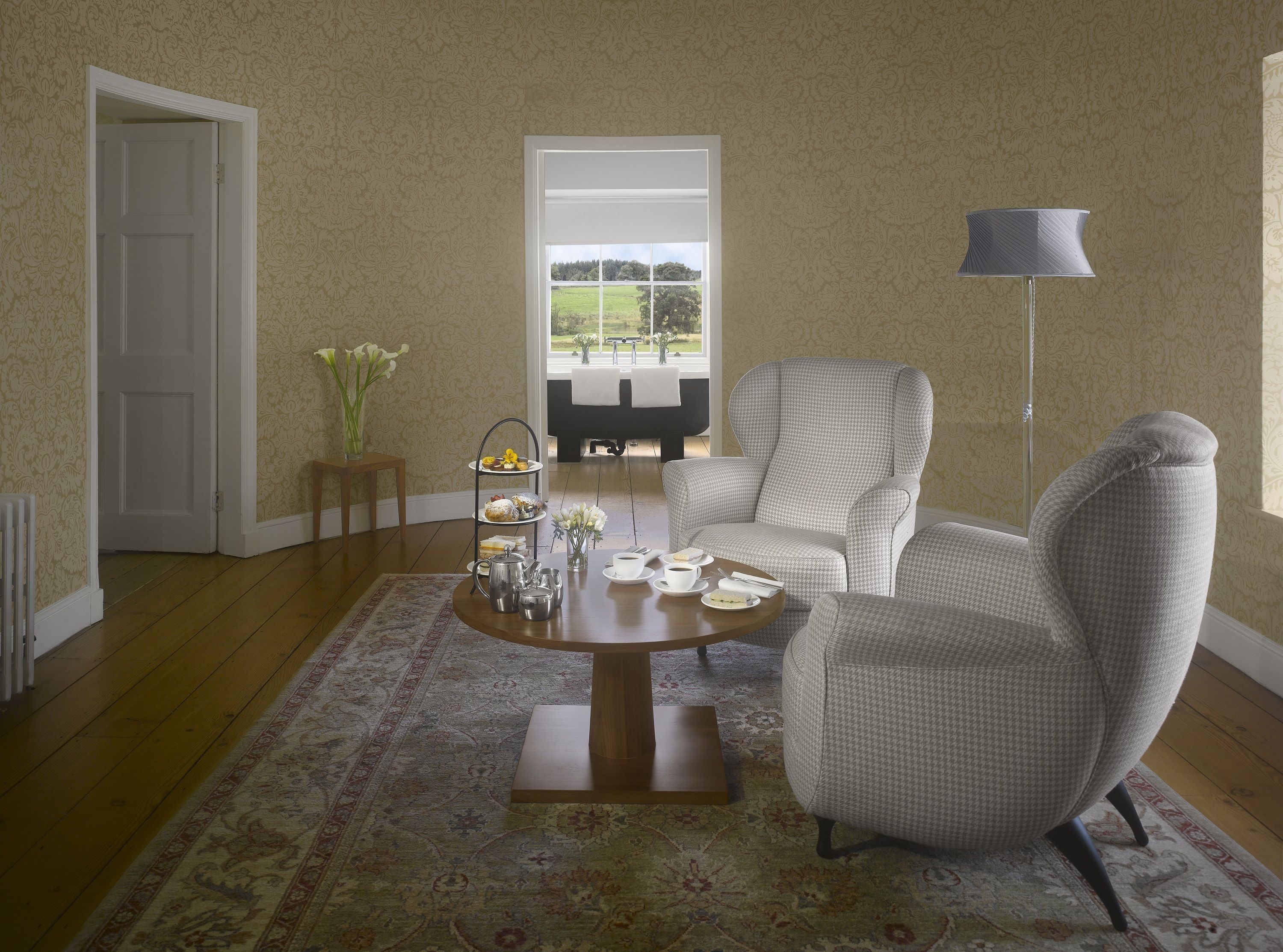 A room with a three-tiered tea service table, a sofa, and a lamp.