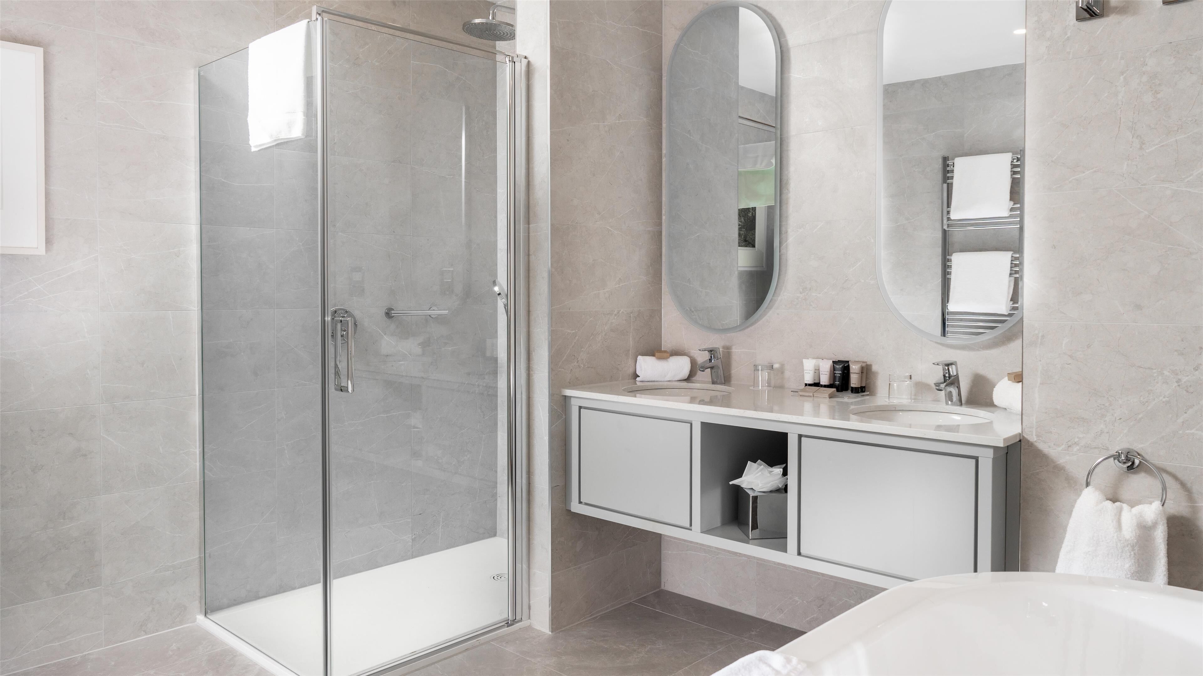 Un baño moderno con ducha envuelta en vidrio, tocador con espejo y bañera.