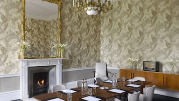 Un comedor formal con una mesa larga, sillas, una chimenea y un espejo grande.