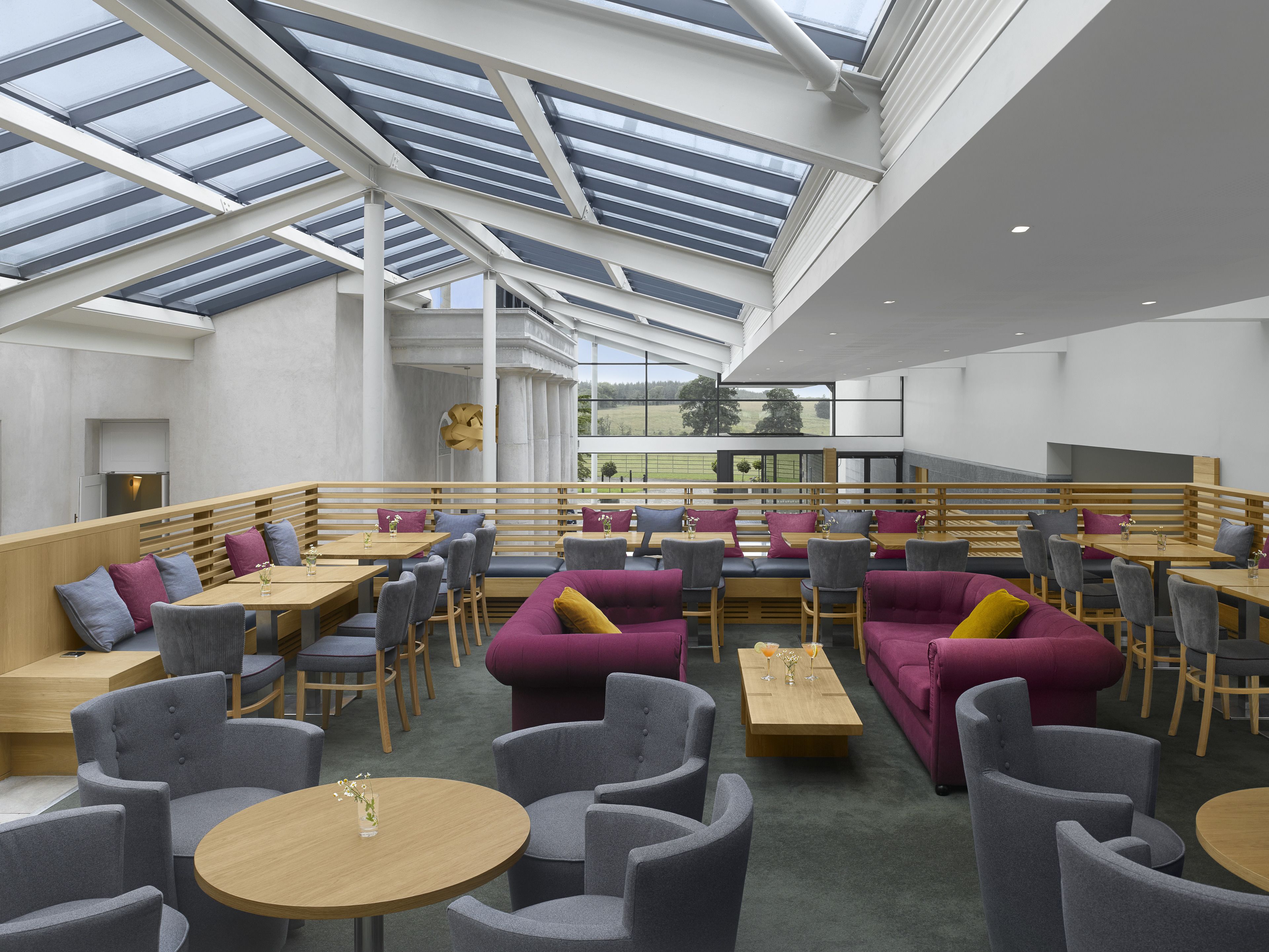 A spacious indoor area with high ceilings and skylights, featuring seating arrangements and tables.