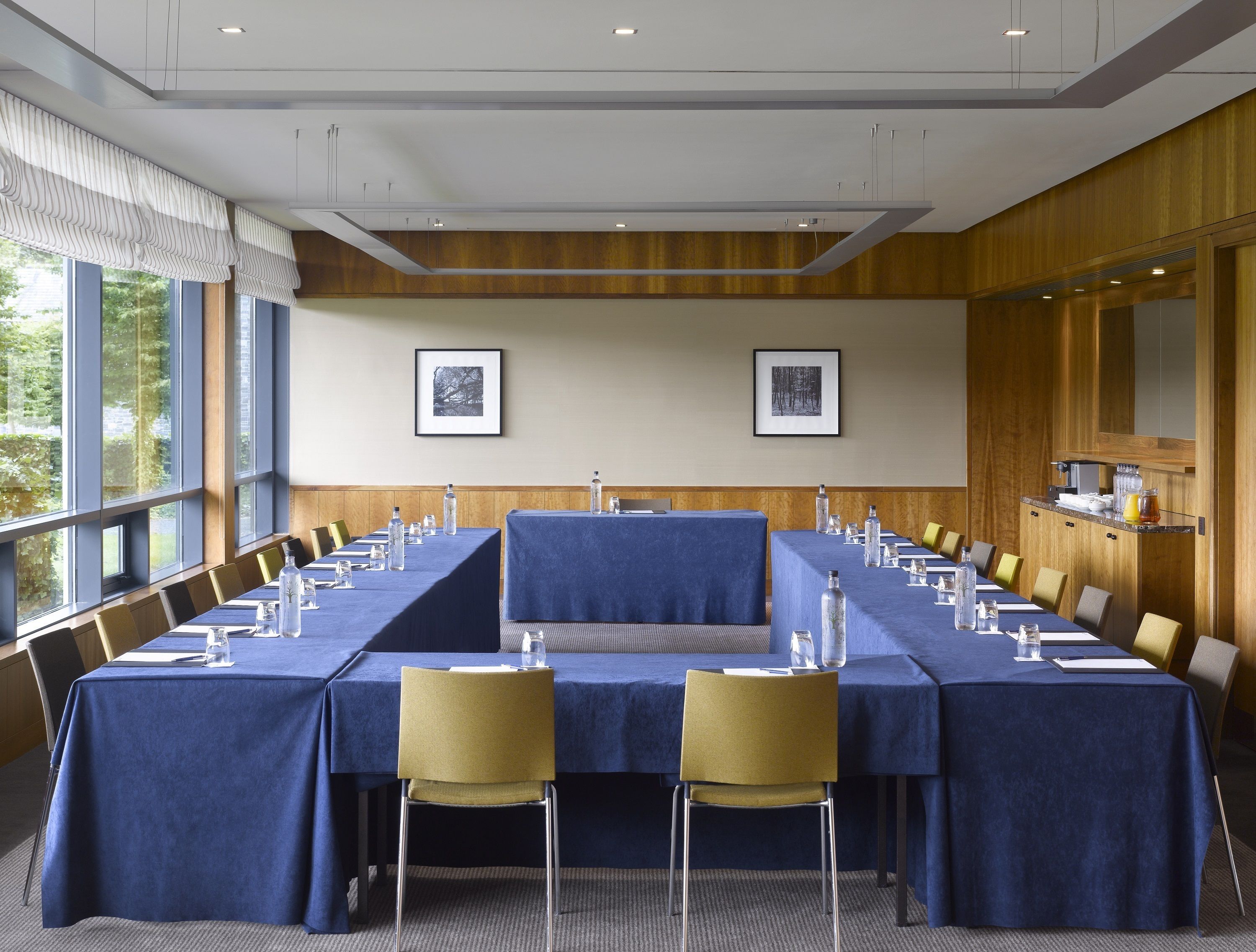 A conference room with a long table, chairs, and framed pictures on the wall.