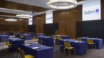 A conference room with tables and chairs, a chandelier, and a Radisson BLU sign.
