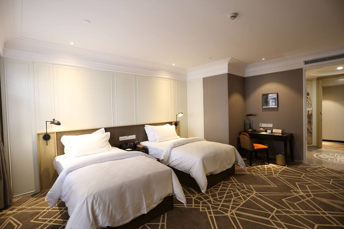 Habitación de hotel con dos camas, un escritorio y una silla.