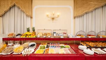 Un bufé con diversos alimentos y bebidas, entre ellos frutas, pasteles y platillos para el desayuno.