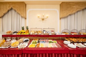 Un bufé con diversos alimentos y bebidas, entre ellos frutas, pasteles y platillos para el desayuno.