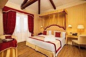 A hotel room with a large bed, a desk, a chair, and a small table.