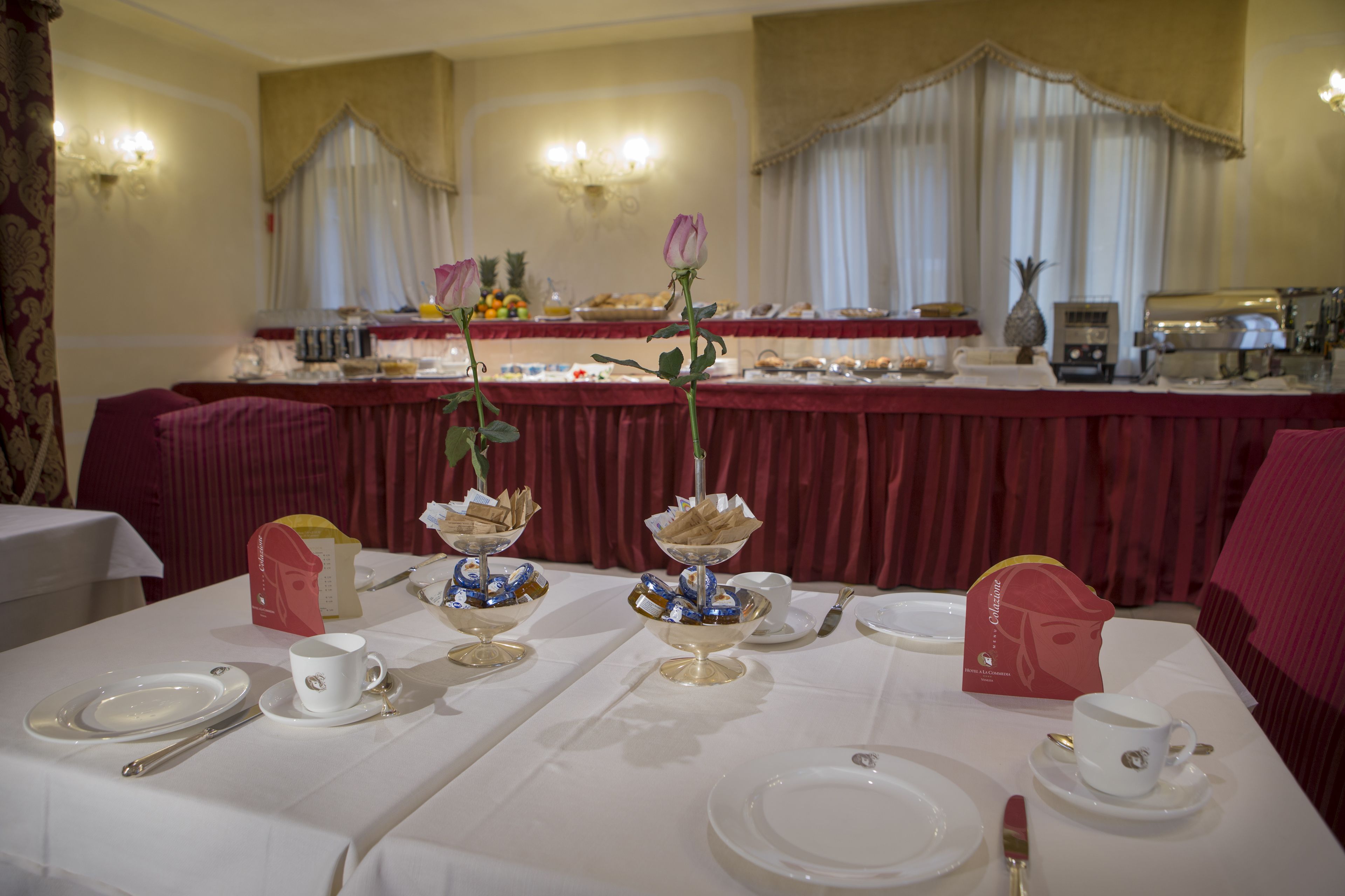 A dining area with tables set for a meal, featuring white tablecloths, silverware, and a red table runner.