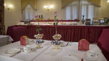 A dining area with tables set for a meal, featuring white tablecloths, silverware, and a red table runner.