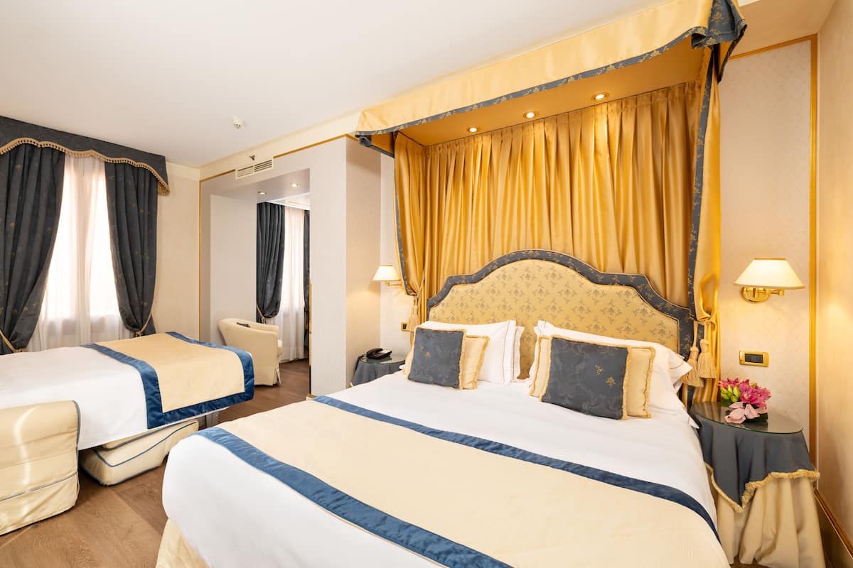 Una habitación de hotel con dos camas, una zona de estar y un baño.