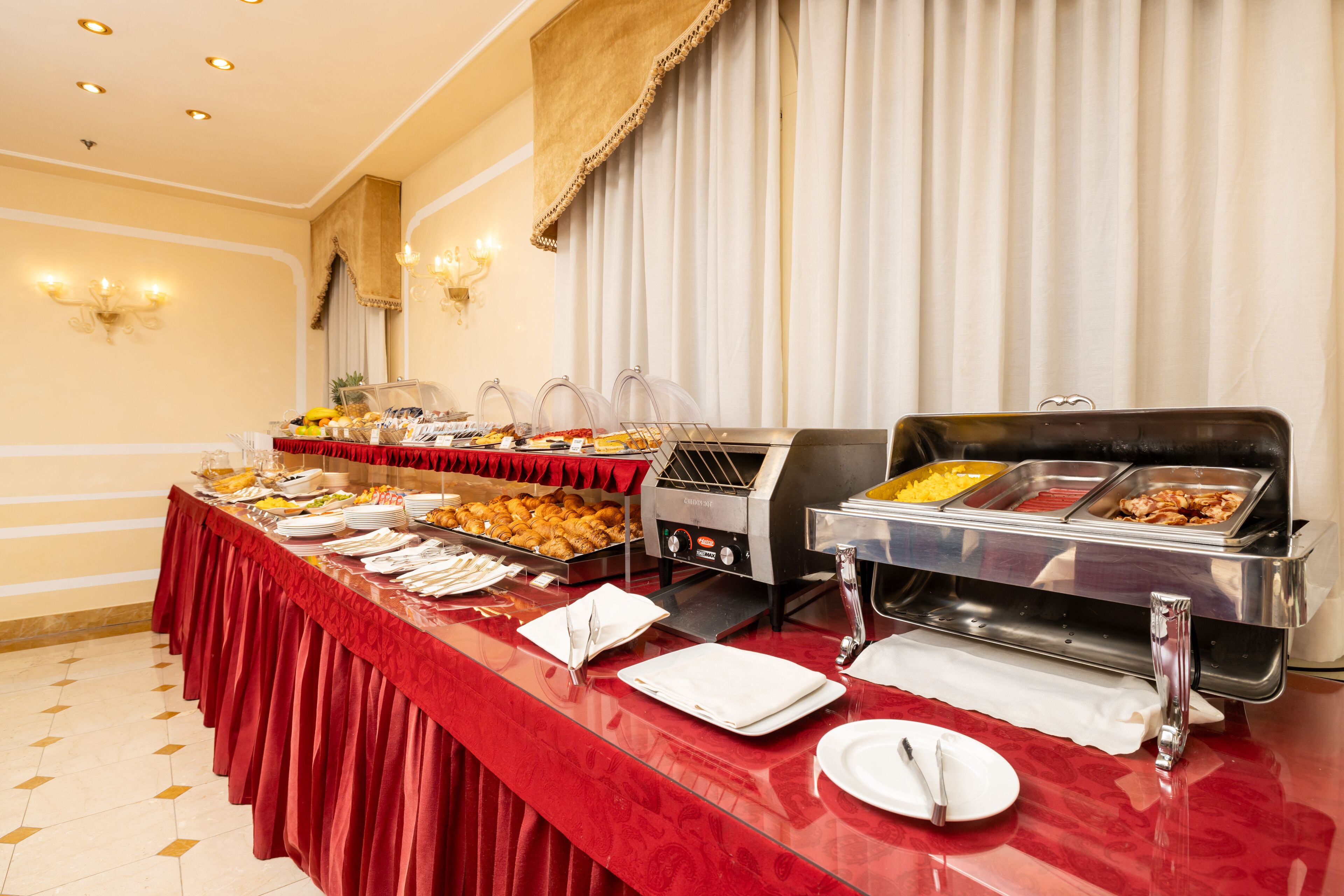 A buffet setup with various food stations, a long table with a red tablecloth, and a grill.