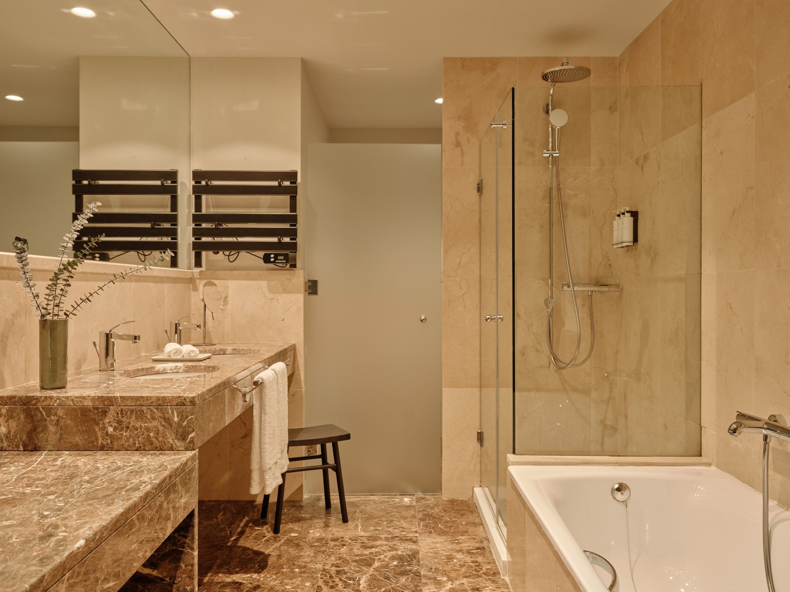 A modern bathroom with a marble sink, a glass-enclosed shower, and a bathtub.