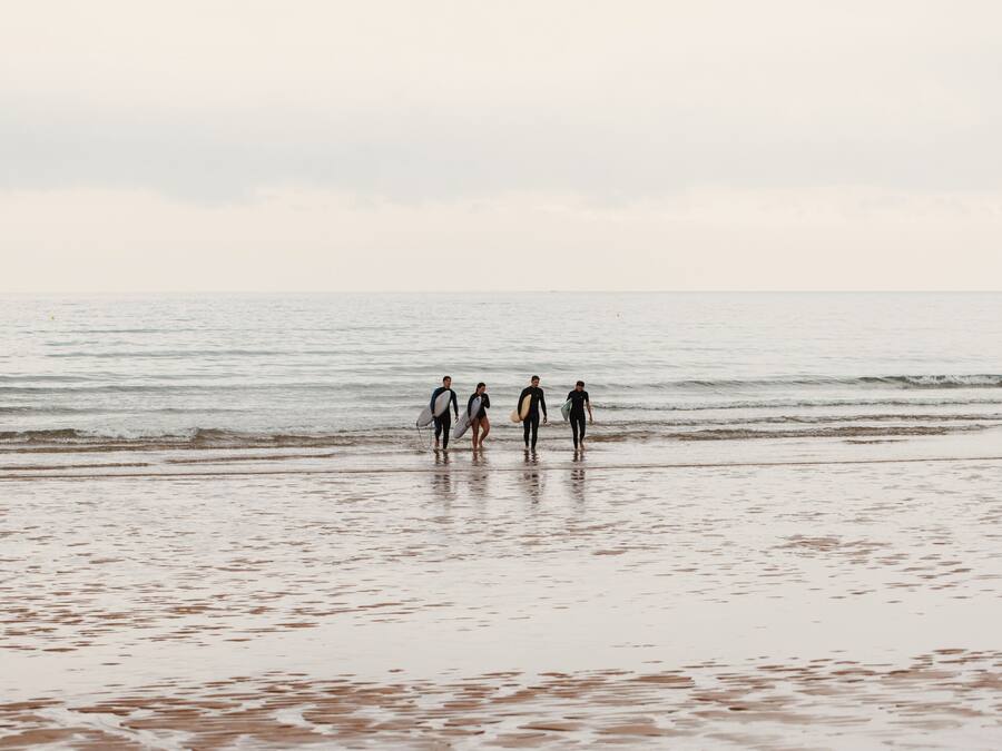 A beach with a group of people walking towards the water.