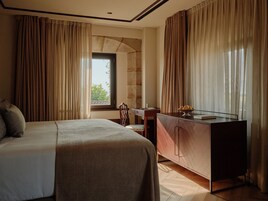 Habitación de hotel con cama, escritorio, armario y ventana con cortinas.