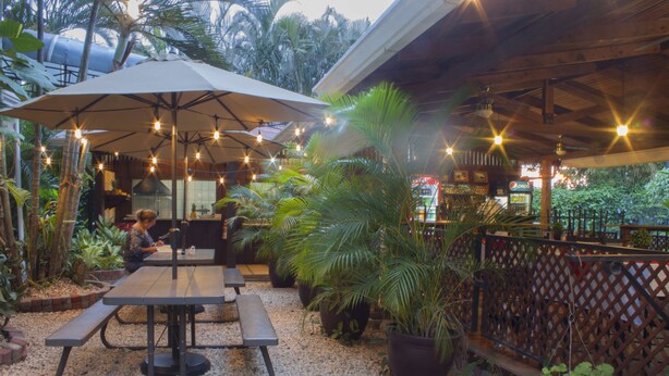 An outdoor patio with tables and benches, surrounded by potted plants and a wooden fence. - Hotel Robledal (San Antonio)