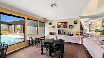A dining area with a pool view, wooden flooring, and a buffet setup.