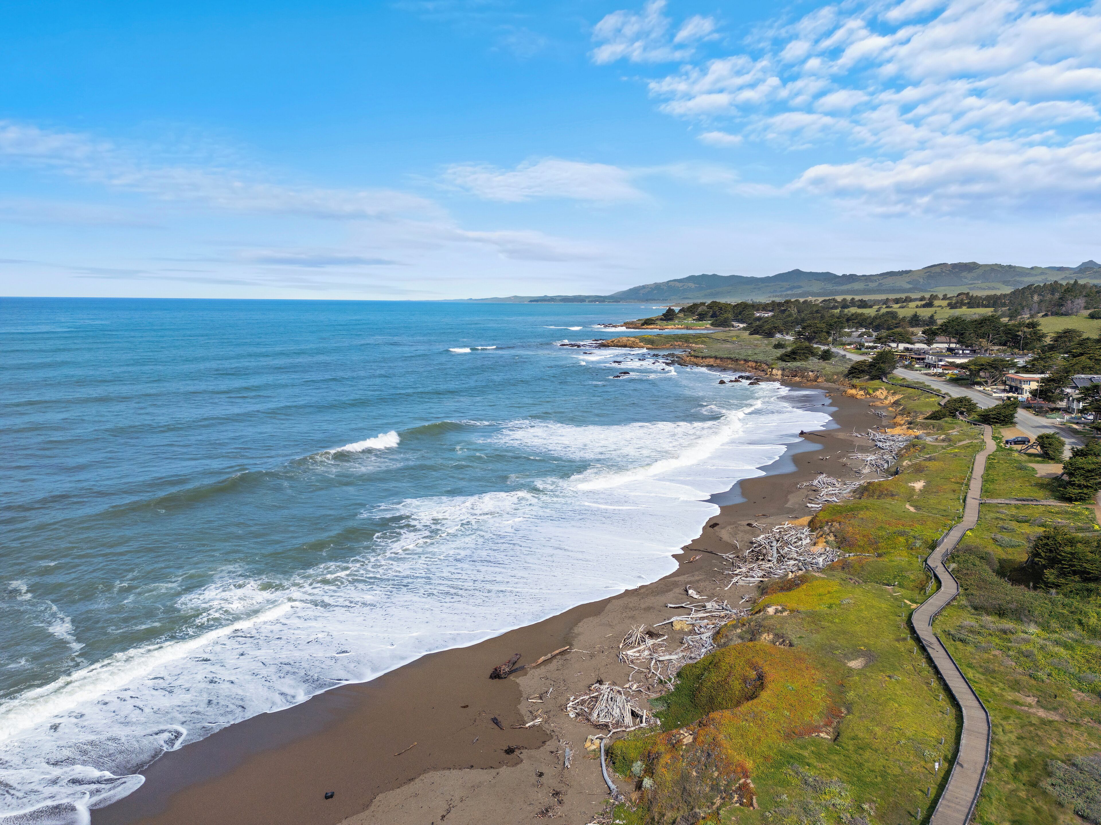 Una carretera costera con una playa a un lado y una zona residencial al otro.