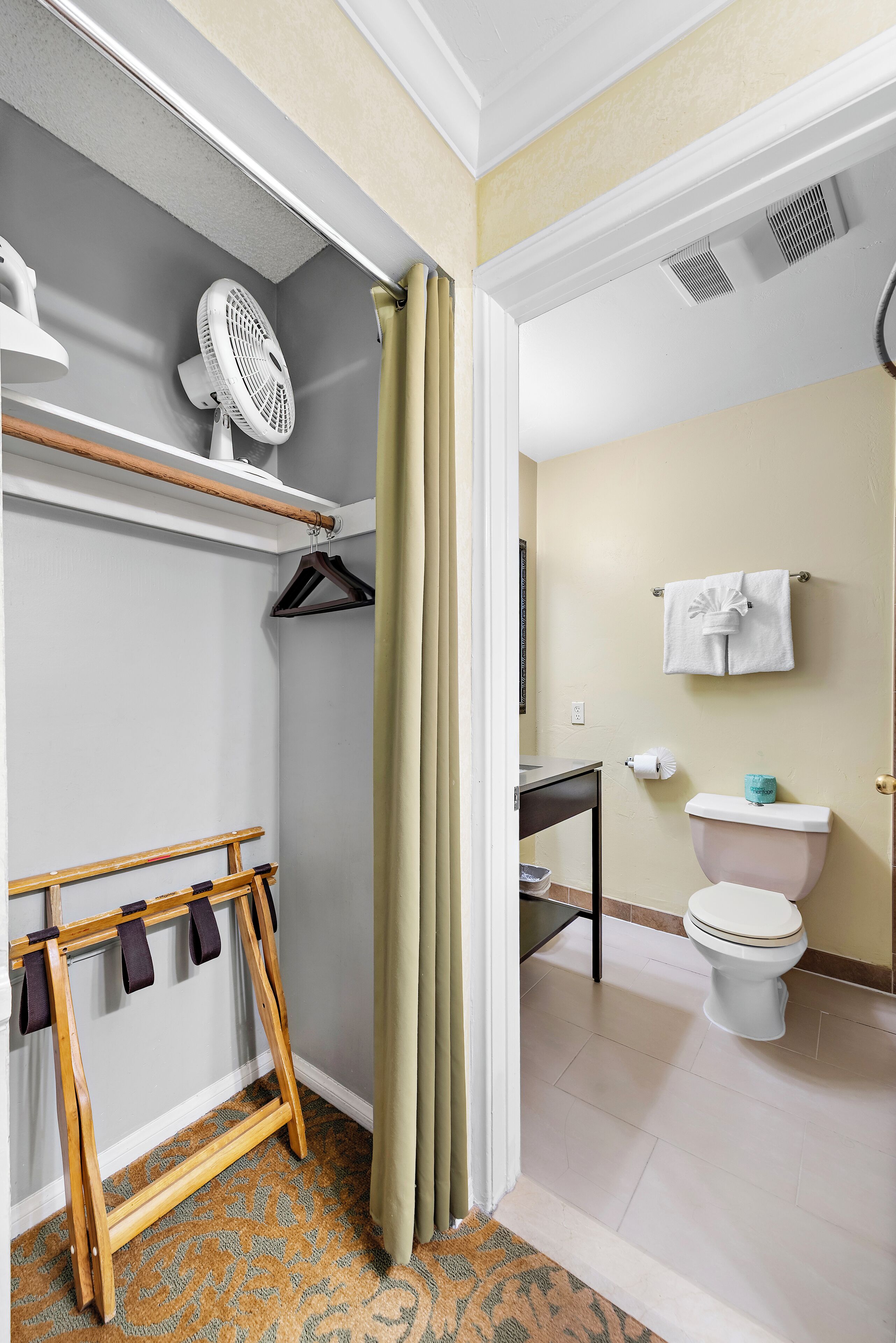 A bathroom with a toilet, a sink, a towel rack, and a fan.
