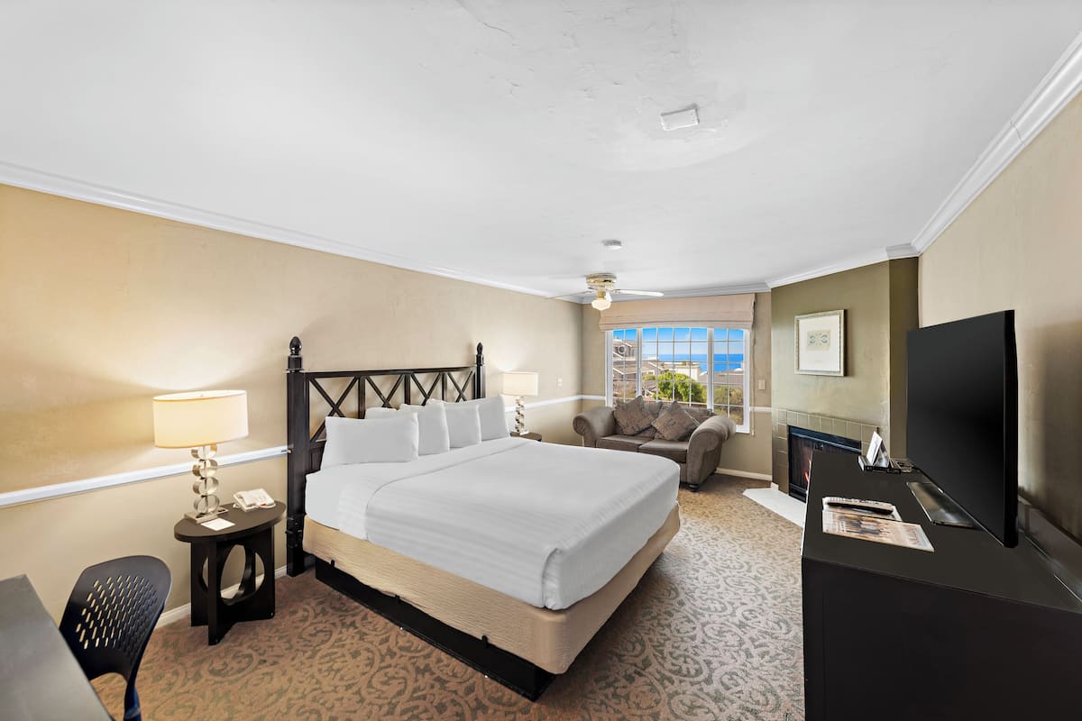 A hotel room with a bed, a TV, a desk, a chair, a lamp, and a window with a view.
