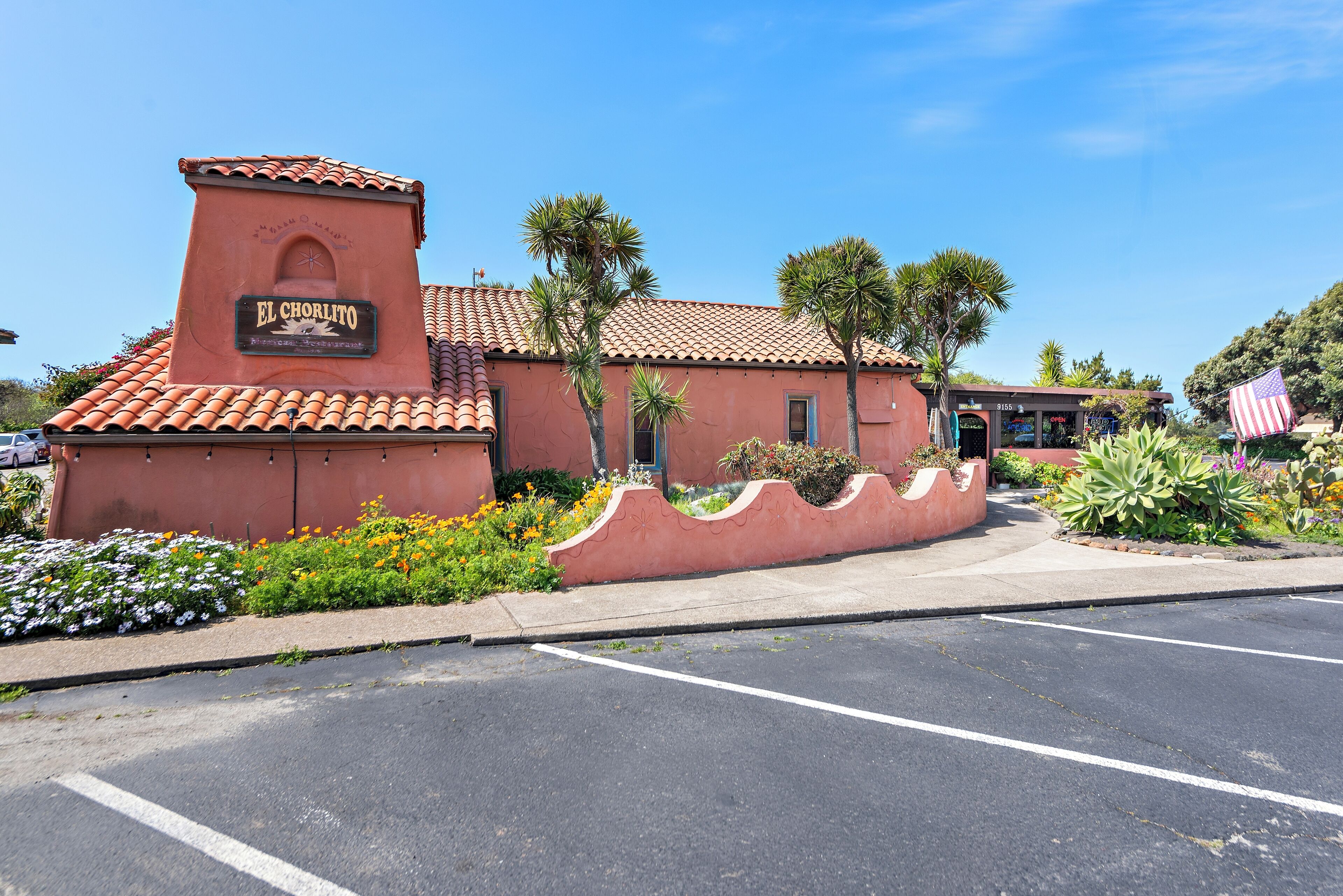 A building with a sign reading "EL CHORLITO American Restaurant" and a parking lot in front.