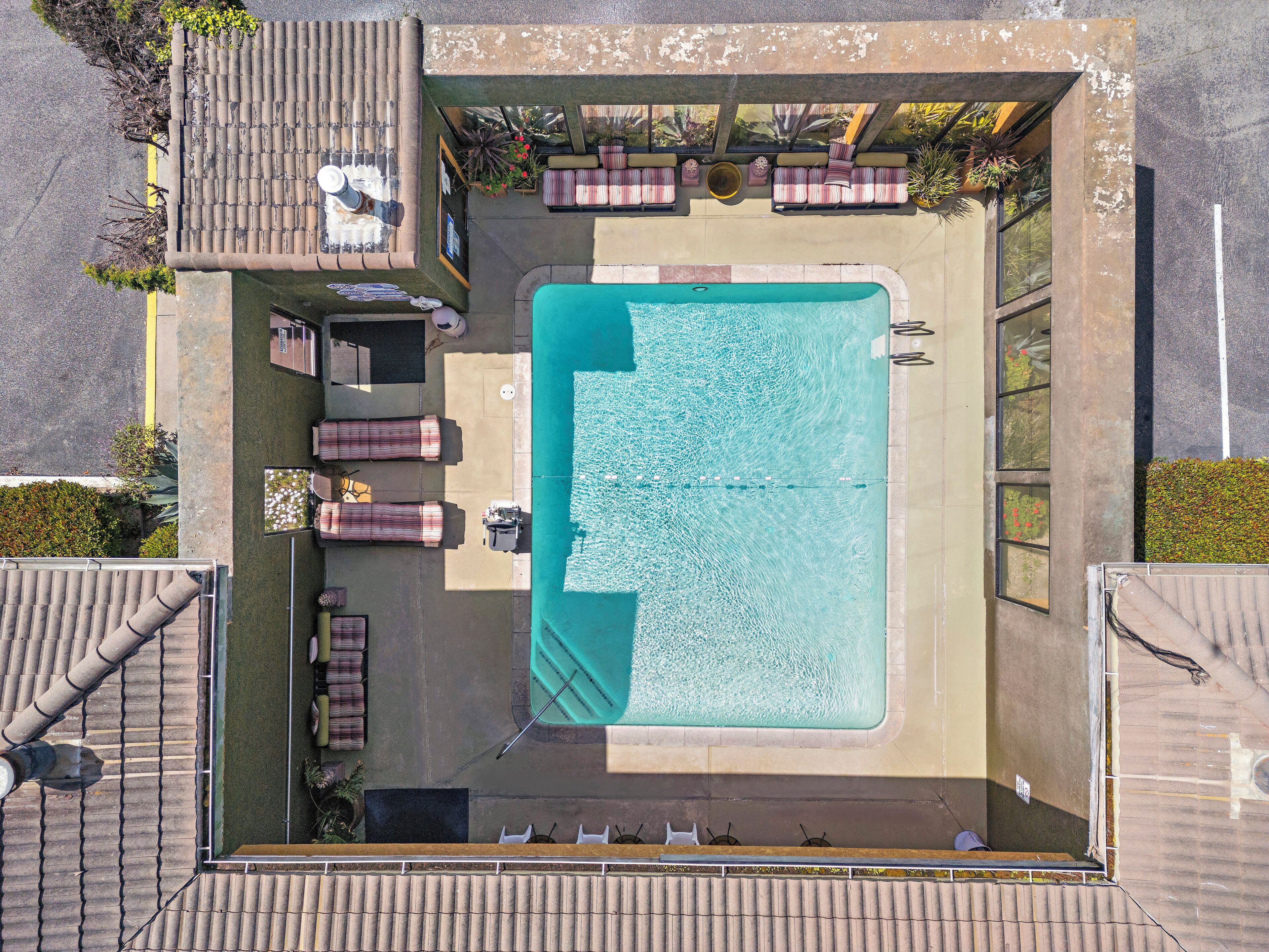 Vista aèria d'una zona de piscina amb gandules i una taula.