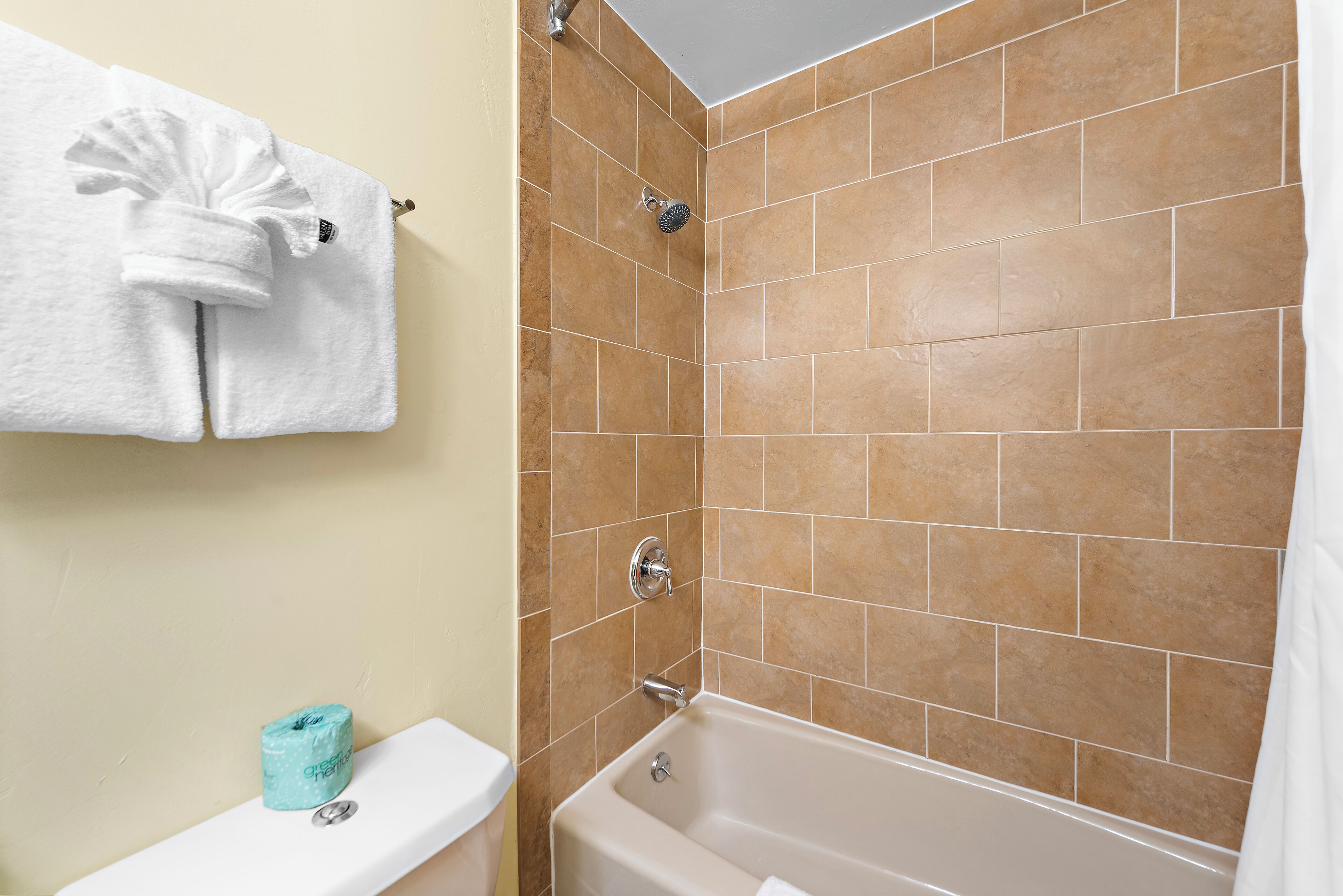 A bathroom with a bathtub, a toilet, and a towel rack with two towels.