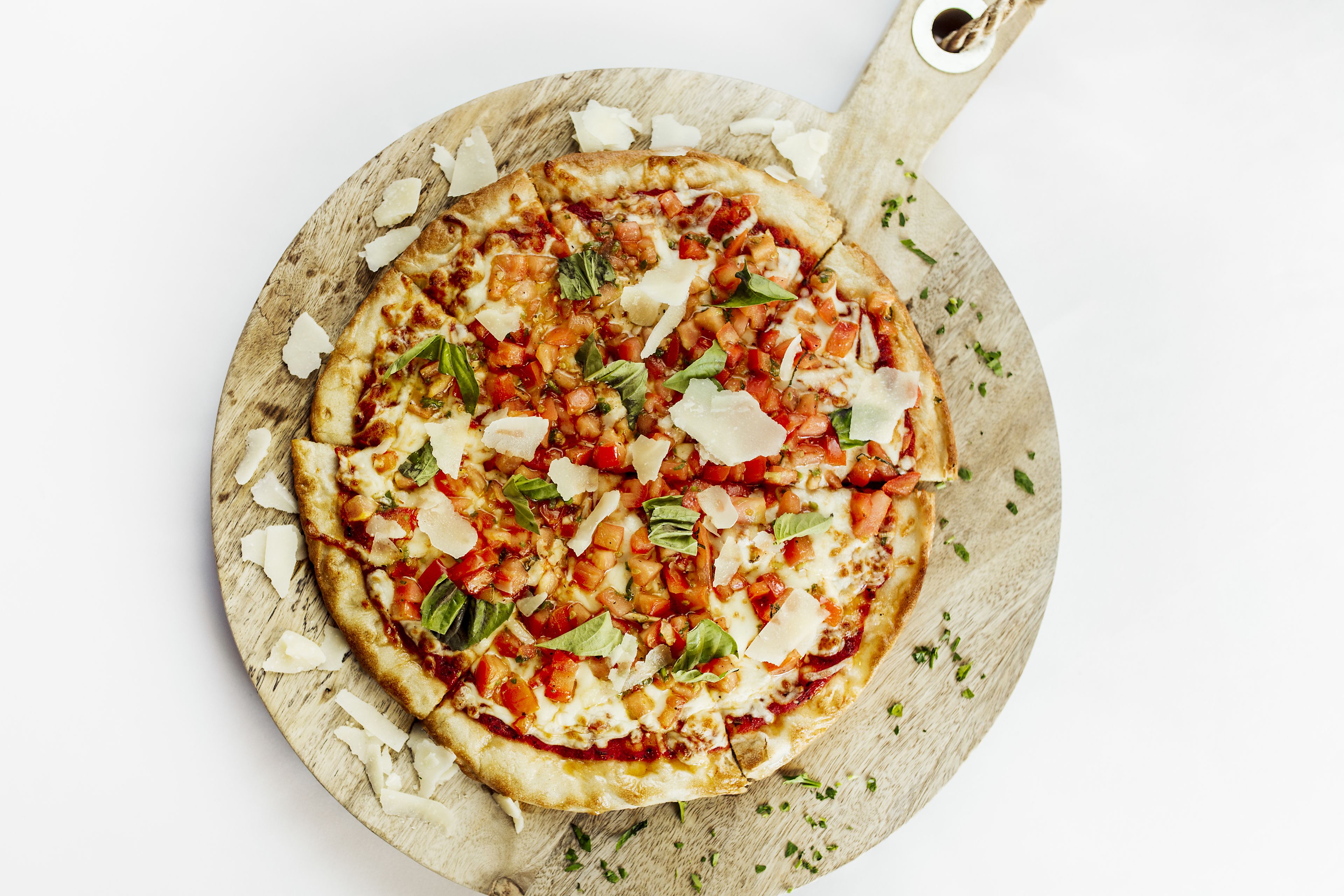 Une pizza servie sur une planche en bois munie d’une anse.
